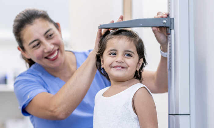 Enfermera Escolar mide la altura de una niña